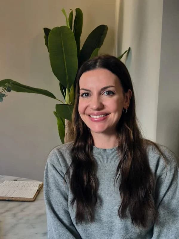 Melanie Hoberg, smiling at a table in a bright room with plants